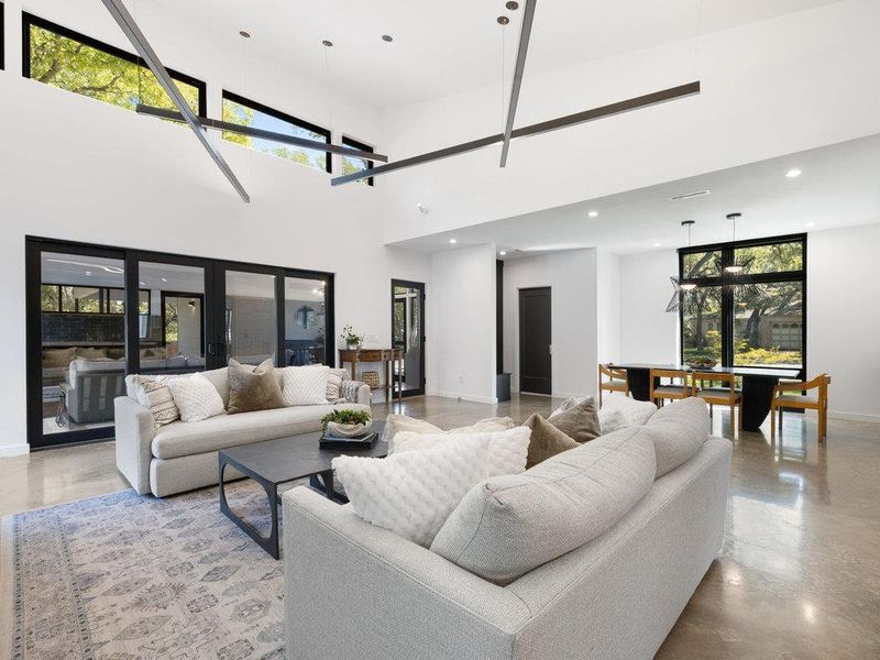 Living area with recessed lighting, finished concrete flooring, and a towering ceiling