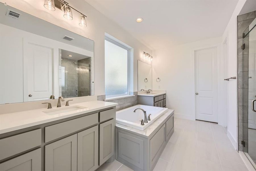 Full bath with a stall shower, two vanities, a garden tub, baseboards, and recessed lighting Full bath with a stall shower, two vanities, a garden tub, baseboards, and recessed lighting