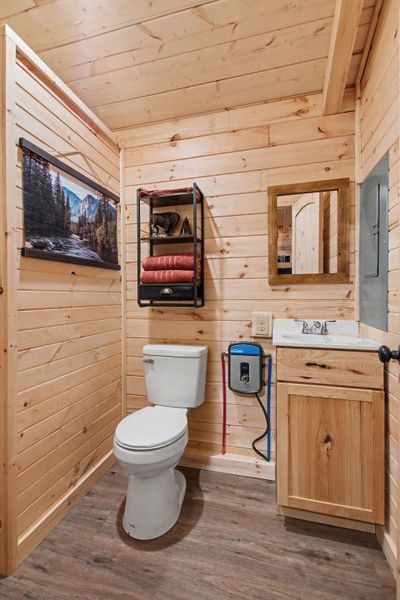 Half bathroom featuring wood walls, vanity, wood ceiling, and light wood-style floors