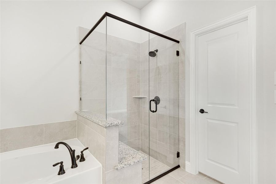 Bathroom with glass-enclosed tile shower, soaking tub, and dark bronze fixtures Bathroom with glass-enclosed tile shower, soaking tub, and dark bronze fixtures