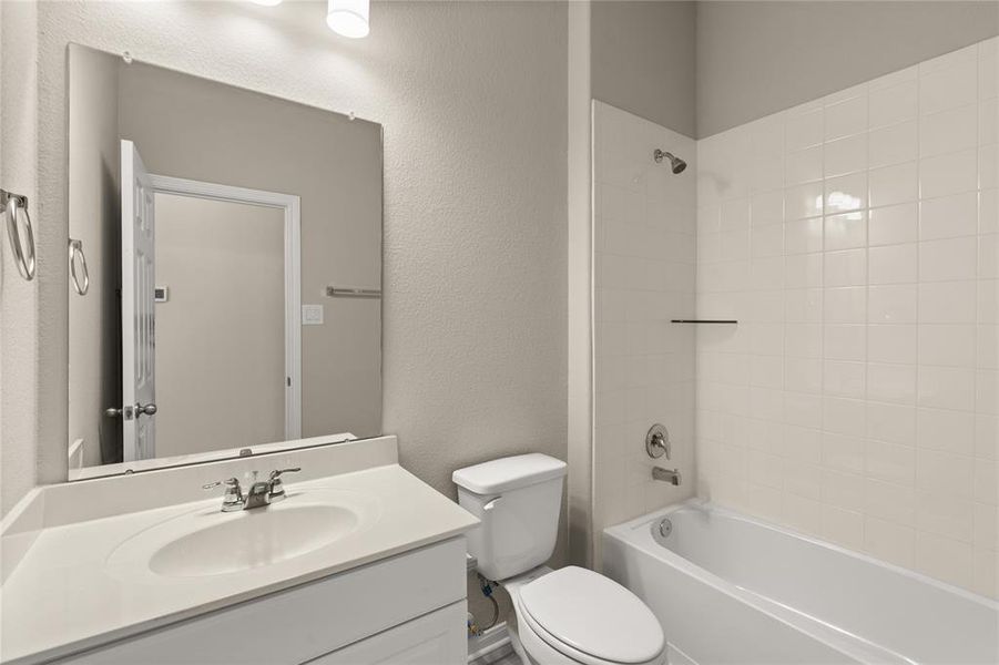 The secondary bath features tile flooring, white cabinetry and light countertops and a shower/tub combo. Perfect for accommodating any visiting family and friends.