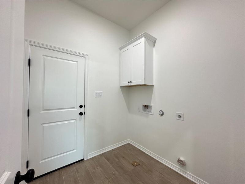 Dedicated utility room featuring wood-finish flooring, white walls, and a white paneled door