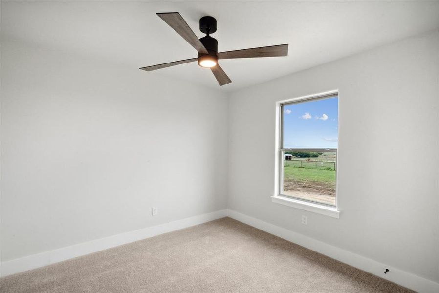 Carpeted empty room featuring ceiling fan