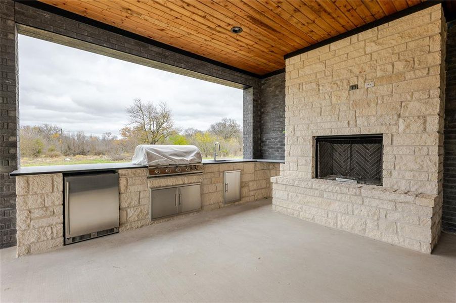 View of patio featuring an outdoor kitchen and an outdoor stone fireplace