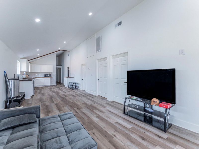 Living room featuring vaulted ceiling, light wood-style flooring, and recessed lighting