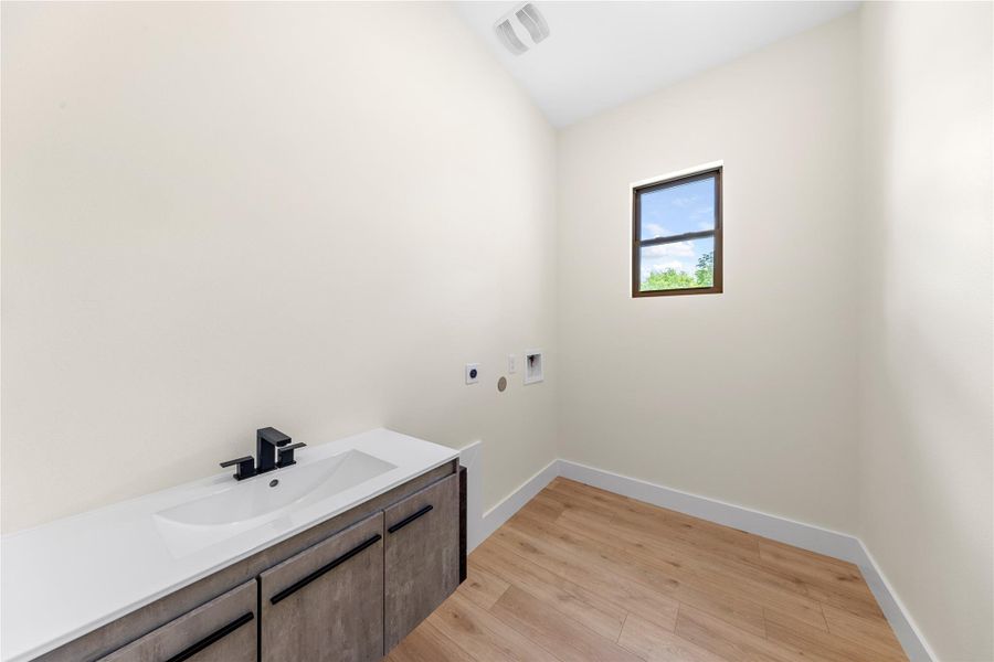 Laundry area with light wood-type flooring, hookup for a washing machine, hookup for an electric dryer, and cabinet space Laundry area with light wood-type flooring, hookup for a washing machine, hookup for an electric dryer, and cabinet space