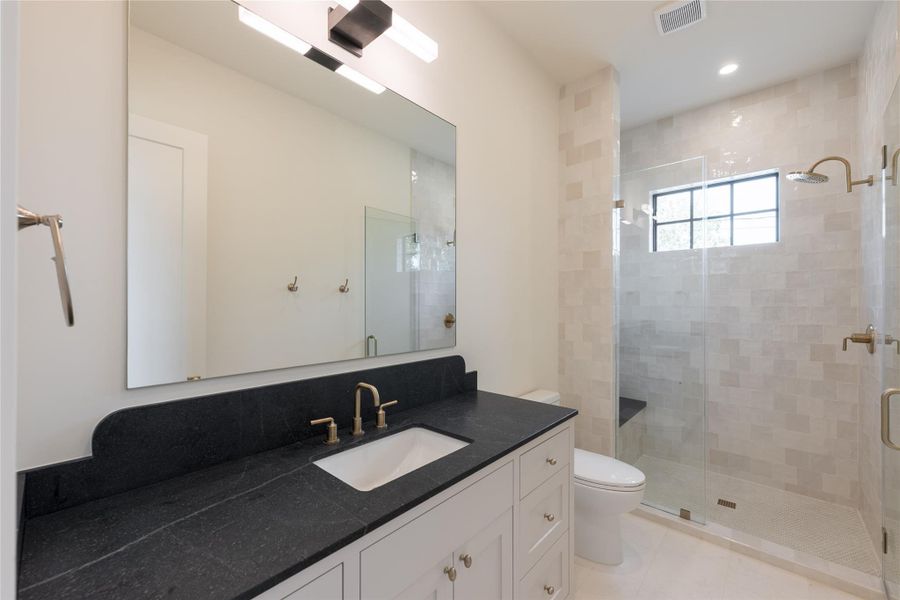 This secondary bathroom is elevated by a striking black countertop with custom curved backsplash detail, brushed brass fixtures, and a walk-in shower wrapped in hand-laid Zellige tile. A large window brings in natural light while offering a private and serene feel. This secondary bathroom is elevated by a striking black countertop with custom curved backsplash detail, brushed brass fixtures, and a walk-in shower wrapped in hand-laid Zellige tile. A large window brings in natural light while offering a private and serene feel.