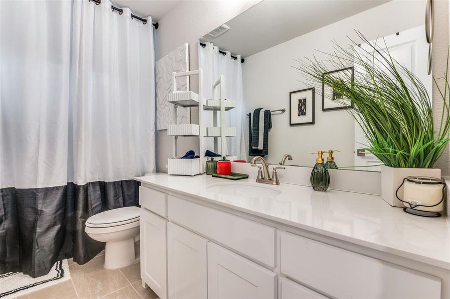 Bathroom featuring vanity, light tile patterned floors, and a shower with shower curtain