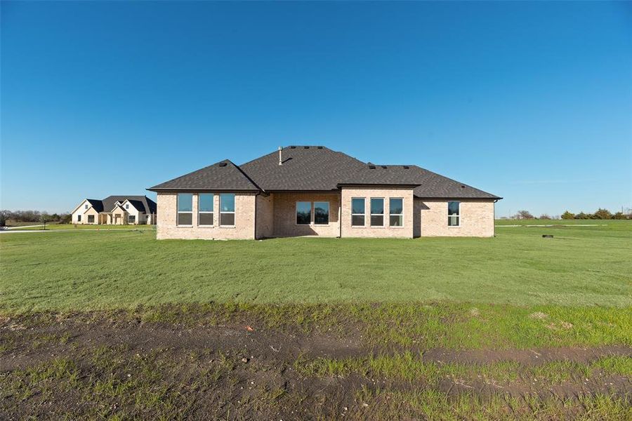 Back of house with a yard, a patio, brick siding, and a shingled roof Back of house with a yard, a patio, brick siding, and a shingled roof