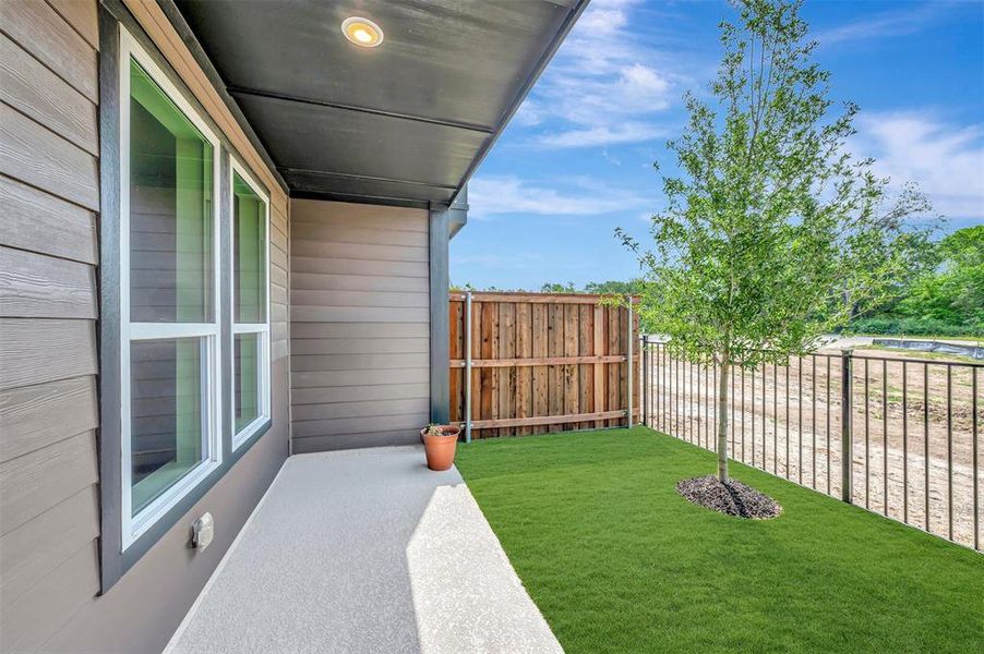 Exterior patio featuring a covered area with recessed lighting, a concrete surface, and a fenced turf section