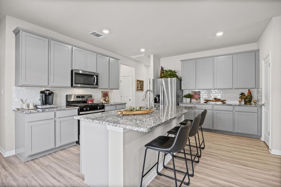 Polished granite countertops and classic shaker cabinetry anchor this light-filled culinary space.