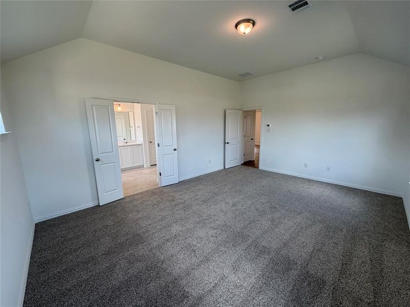 Spacious room featuring vaulted ceilings, plush carpeting, bright white walls, and elegant French doors