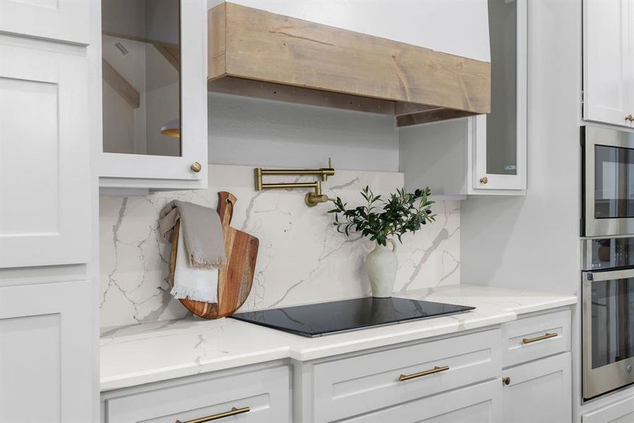 Kitchen featuring light stone counters, tasteful backsplash, appliances with stainless steel finishes, and white cabinets