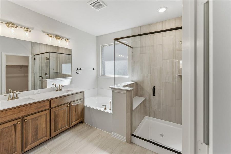 Bathroom featuring a spacious closet, double vanity, a shower stall, and a bath