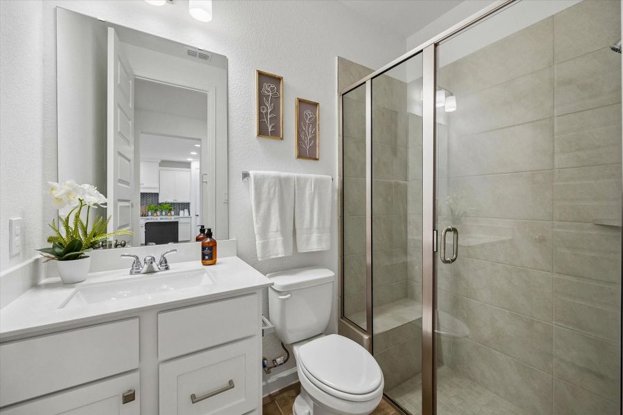 The 1st -floor full bathroom is conveniently located near the guest bedroom, offering easy access for visitors and everyday use. A walk-in shower, clean finishes, and a single sink vanity make this space both practical and polished.