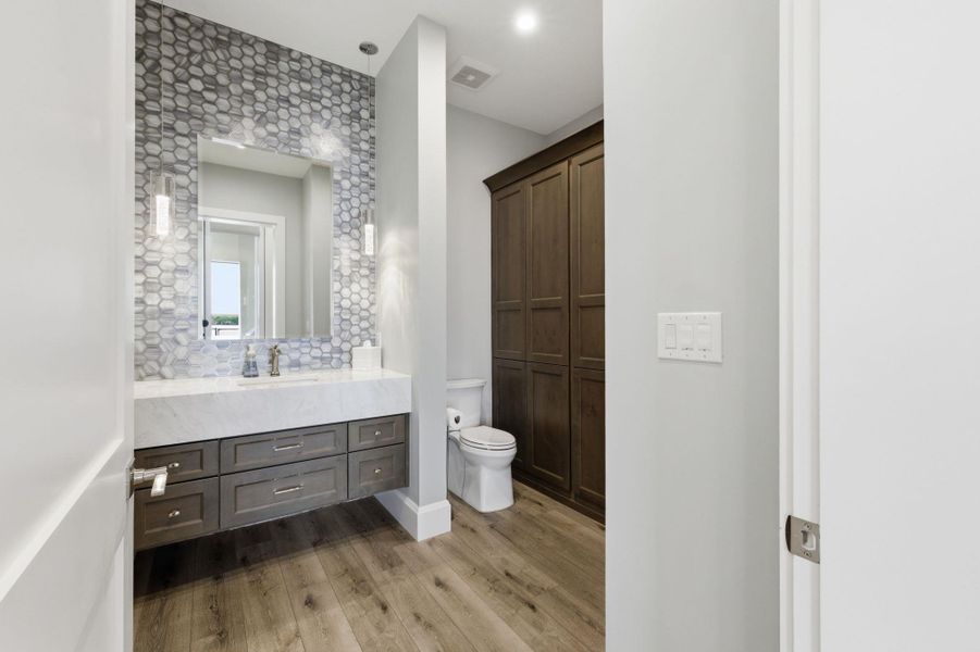 Full bath featuring vanity, light wood-style flooring, and decorative backsplash