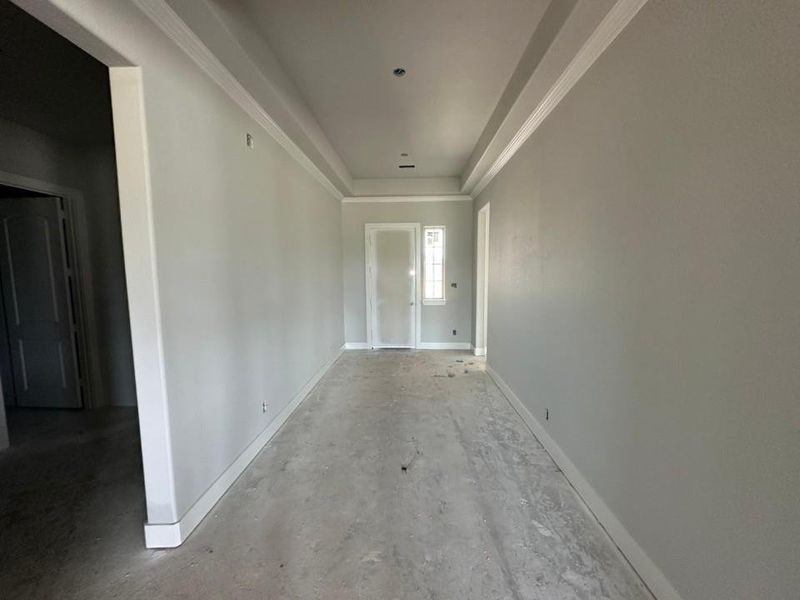 Interior hallway featuring light gray walls, white baseboards, and white crown molding