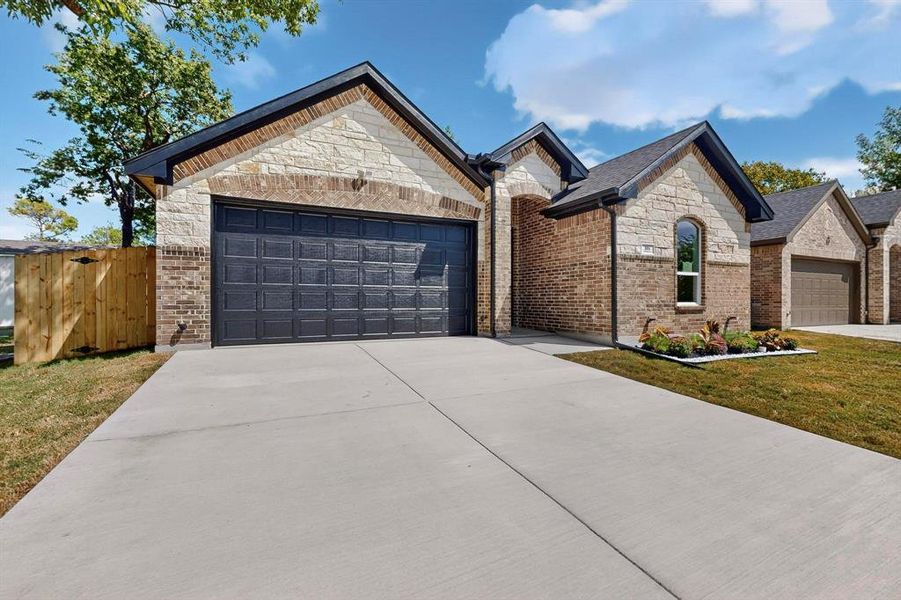 French provincial home with brick siding, stone siding, driveway, and an attached garage