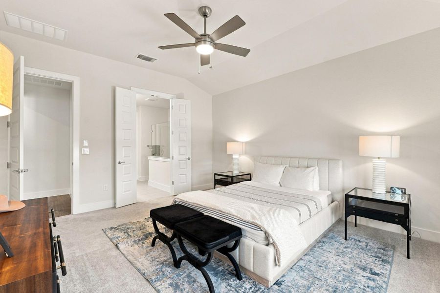 Primary bedroom retreat featuring a vaulted ceiling, modern ceiling fan, plush carpet, and double doors leading into the en-suite bath. Primary bedroom retreat featuring a vaulted ceiling, modern ceiling fan, plush carpet, and double doors leading into the en-suite bath.