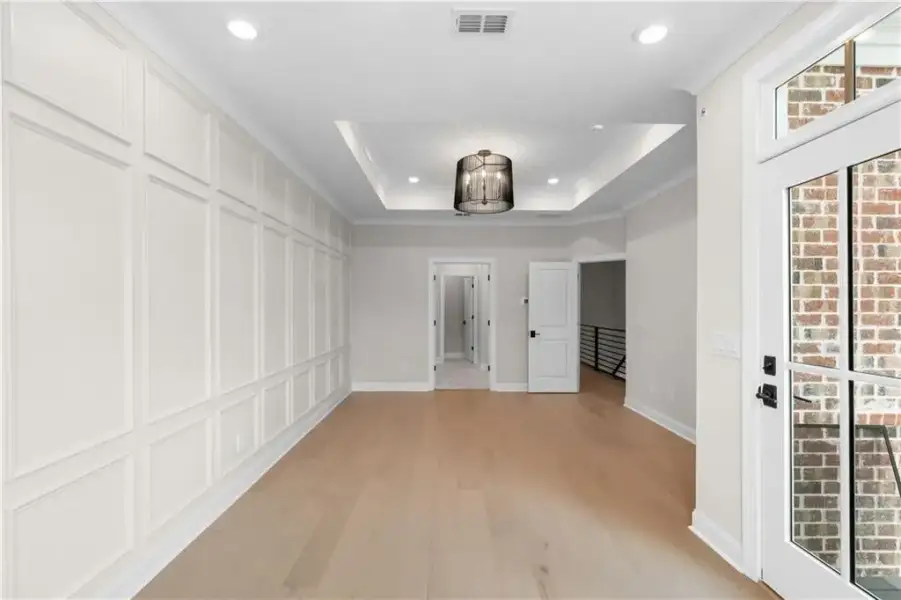 Recessed lighting, tray ceiling, and a modern chandelier illuminate the room