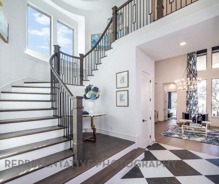 Stairs with an inviting chandelier, baseboards, a towering ceiling, and recessed lighting Stairs with an inviting chandelier, baseboards, a towering ceiling, and recessed lighting