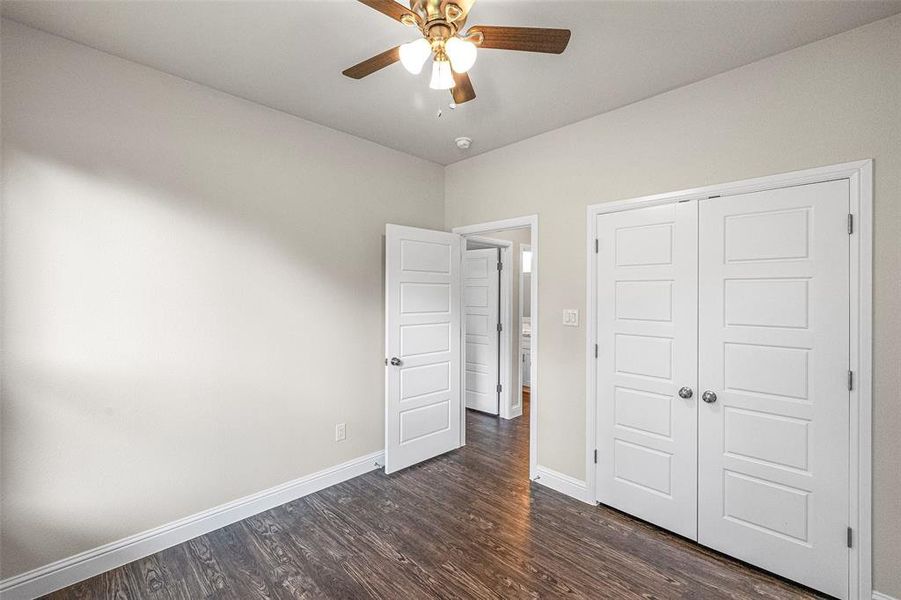 Unfurnished bedroom with a closet, ceiling fan, and dark hardwood / wood-style flooring