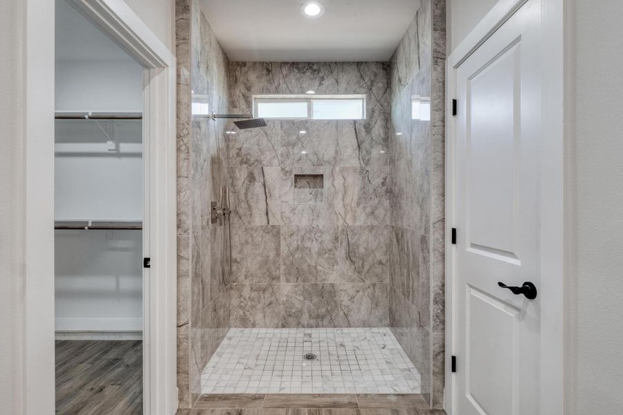 Bathroom featuring a marble finish shower and a walk in closet