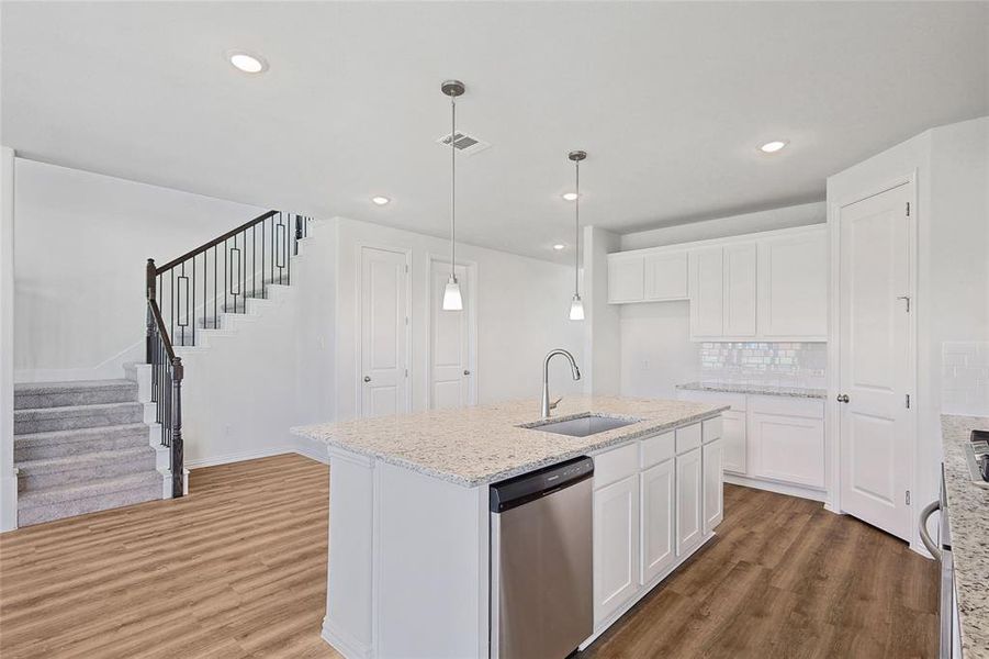 Kitchen with white cabinetry, stainless steel dishwasher, hardwood / wood-style flooring, and sink