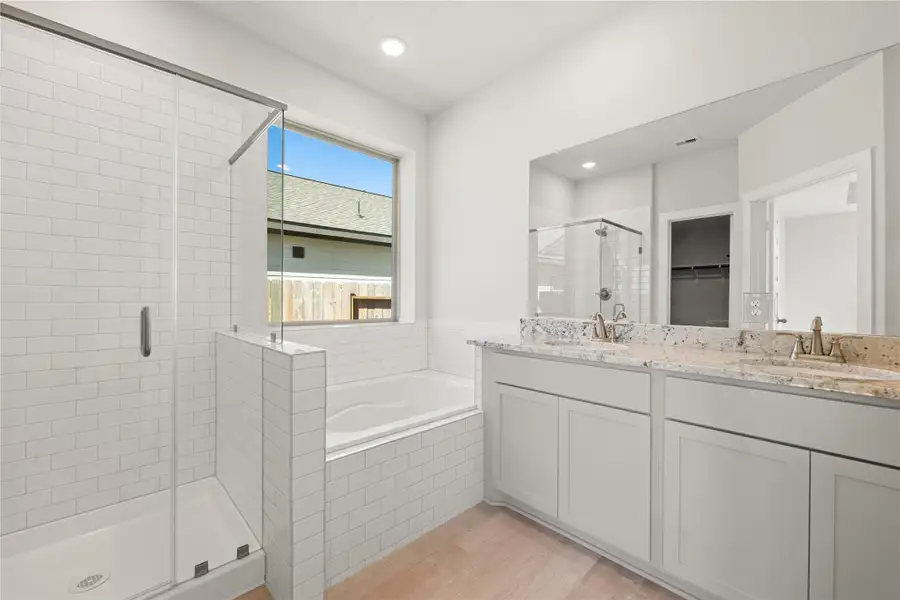This elegant primary bath features a soaking tub, separate glass-enclosed shower, and dual vanities with ample counter space. Soft natural light and modern finishes create a clean, refreshing atmosphere. This elegant primary bath features a soaking tub, separate glass-enclosed shower, and dual vanities with ample counter space. Soft natural light and modern finishes create a clean, refreshing atmosphere.
