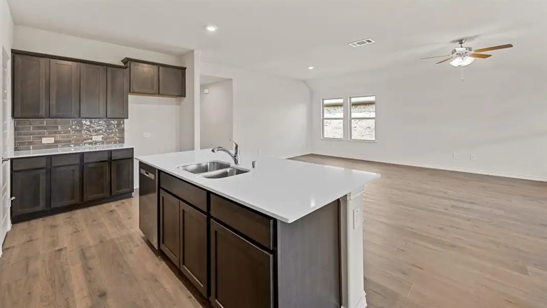 Kitchen island featuring a dual-basin stainless steel sink, a stainless steel faucet, and a dishwasher Kitchen island featuring a dual-basin stainless steel sink, a stainless steel faucet, and a dishwasher