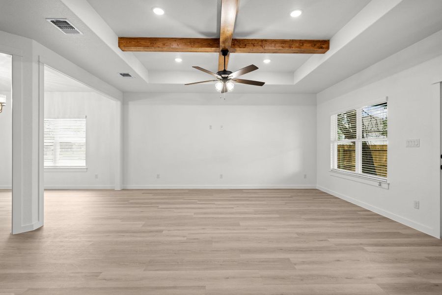 A spacious living area offers wood-look flooring and a unique beamed tray ceiling with a modern fan. A spacious living area offers wood-look flooring and a unique beamed tray ceiling with a modern fan.