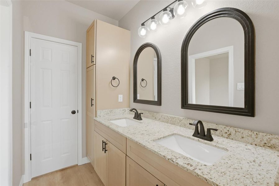 Bathroom with double vanity and light wood-style flooring