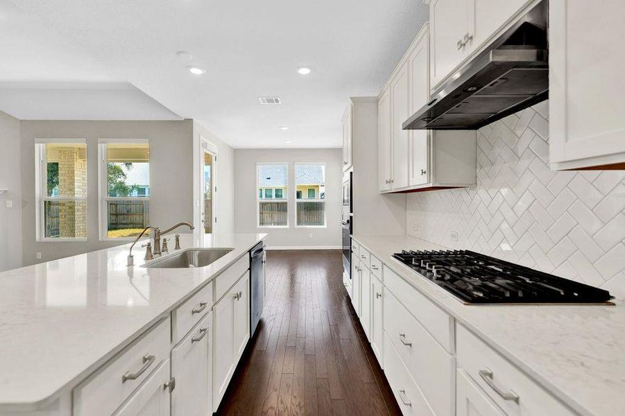 Kitchen with white cabinetry, light stone counters, under cabinet range hood, appliances with stainless steel finishes, and recessed lighting Kitchen with white cabinetry, light stone counters, under cabinet range hood, appliances with stainless steel finishes, and recessed lighting