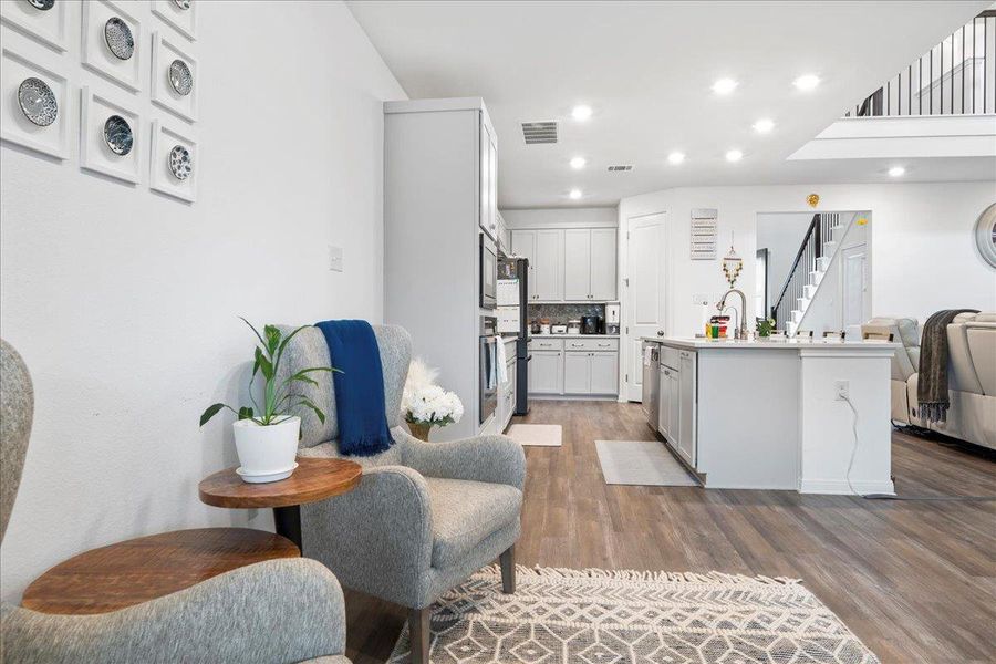 Kitchen featuring recessed lighting, open floor plan, light countertops, dark wood finished floors, and a center island with sink
