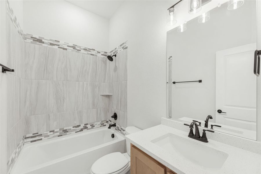 Bathroom with tiled tub-shower combo, quartz vanity, and black fixtures