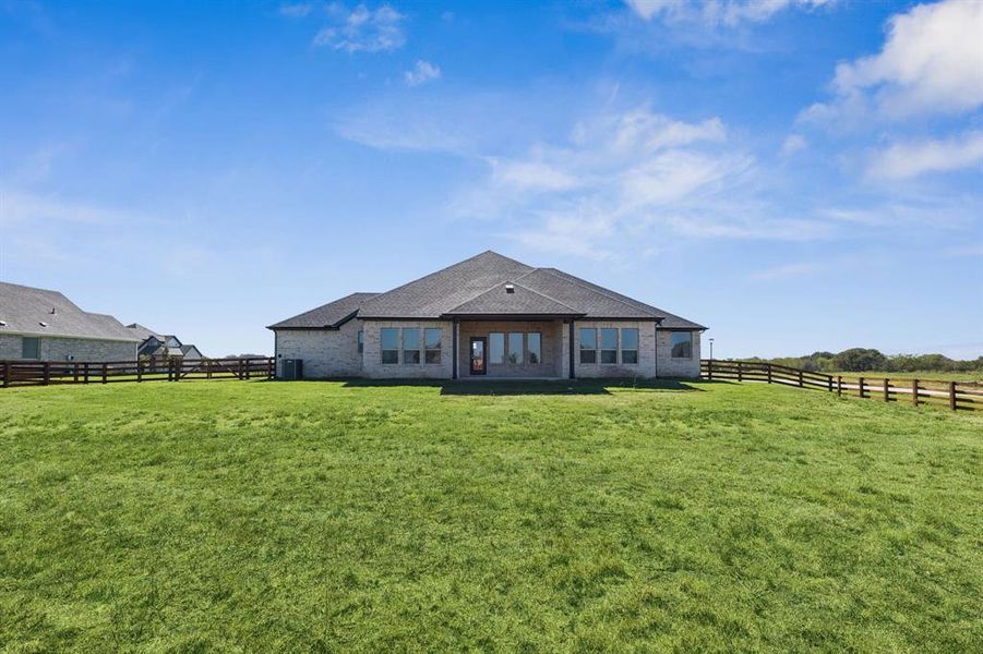 Back of property with a fenced backyard, a patio, brick siding, and a view of rural / pastoral area
