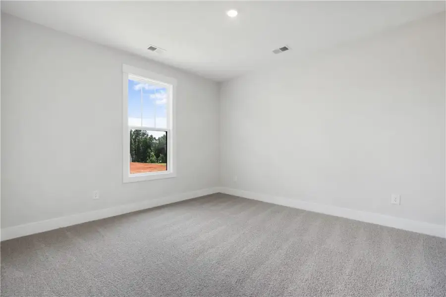 Well-lit room featuring soft gray carpeting and a Well-lit room featuring soft gray carpeting and a