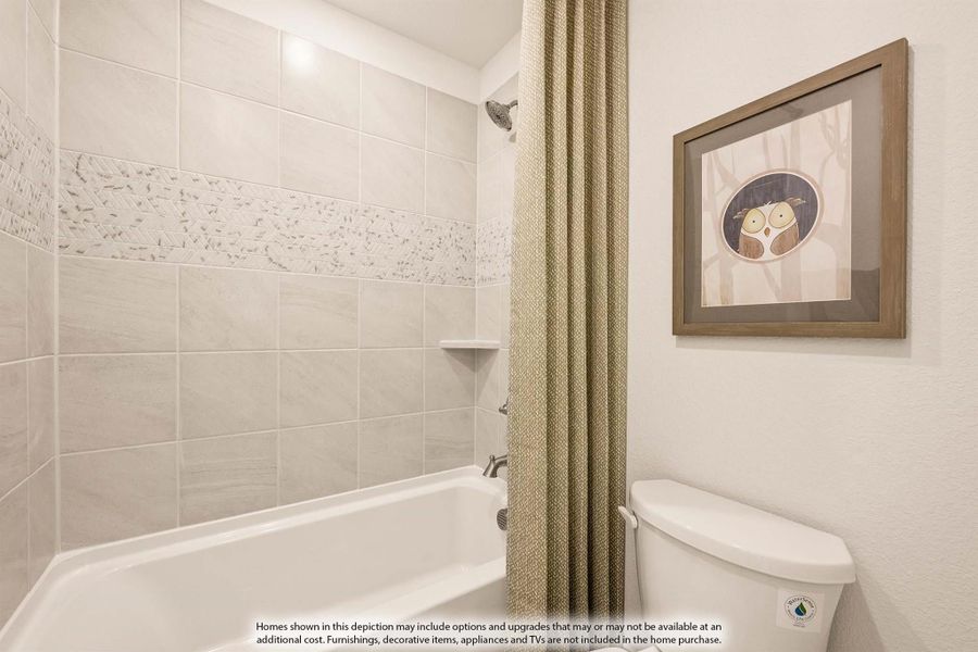 Bathroom with tiled shower-tub combo, beige curtain, toilet, and framed owl artwork on the wall