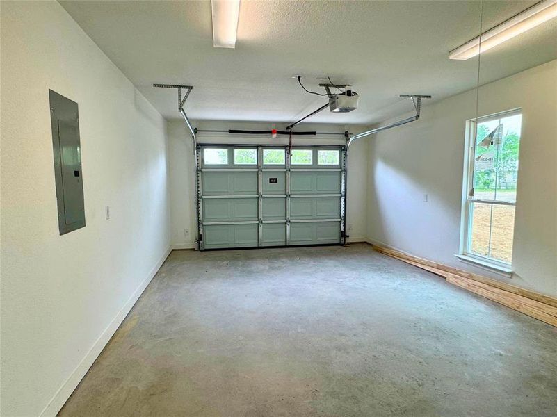 Garage with baseboards, a garage door opener, and electric panel