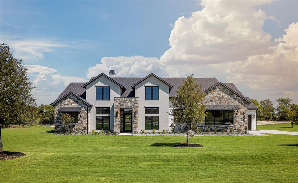View of front of house featuring stone siding, a front yard, stucco siding, and a standing seam roof