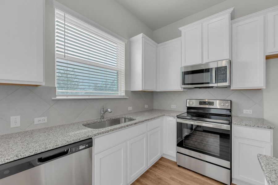 Kitchen with appliances with stainless steel finishes and white cabinetry