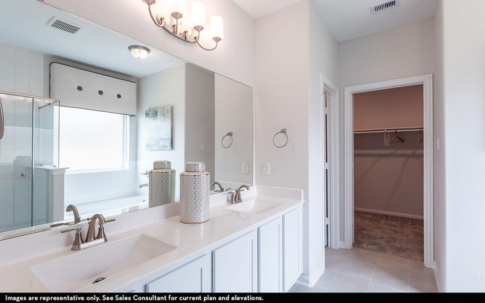Full bathroom featuring a spacious closet, a shower stall, double vanity, a bath, and light tile patterned flooring