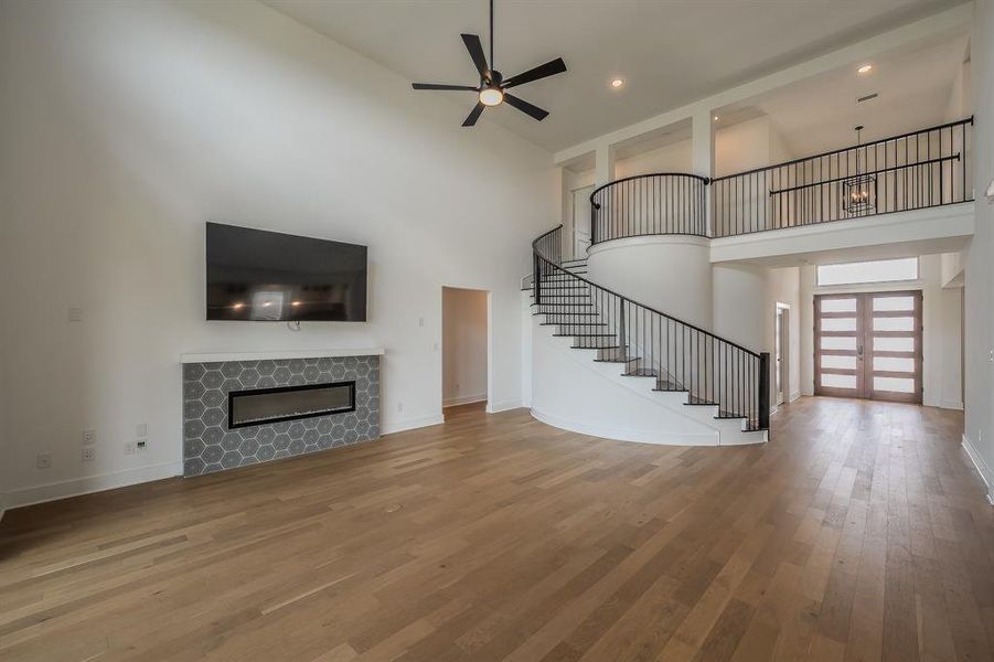 This spacious interior features light-colored hardwood flooring, a modern fireplace with hexagonal tile surround, and a ceiling fan