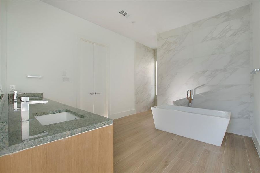 Bathroom featuring a bath, tile walls, hardwood / wood-style floors, and vanity