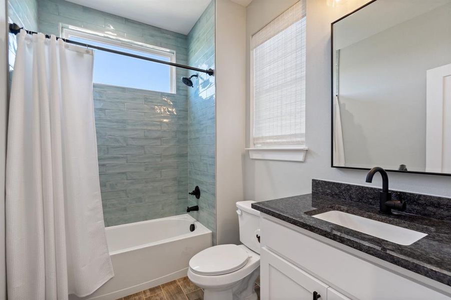 Full bathroom featuring wood-type flooring, vanity, toilet, and shower / tub combo with curtain