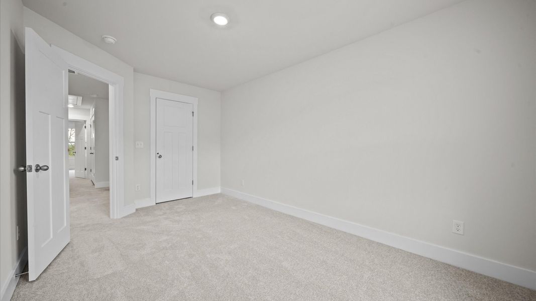 Tasteful secondary bedroom with plush carpet and a spacious walk-in closet Tasteful secondary bedroom with plush carpet and a spacious walk-in closet