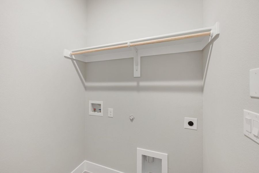 Laundry room with white shelf, hanging rod, washer hookups, and dryer vent connection on gray walls