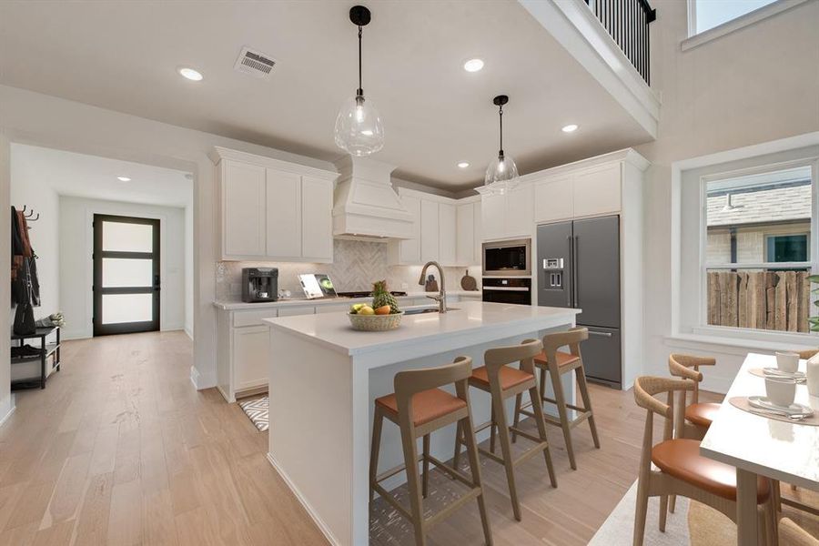 Kitchen with appliances with stainless steel finishes, light wood-style floors, decorative backsplash, a kitchen breakfast bar, and recessed lighting Kitchen with appliances with stainless steel finishes, light wood-style floors, decorative backsplash, a kitchen breakfast bar, and recessed lighting
