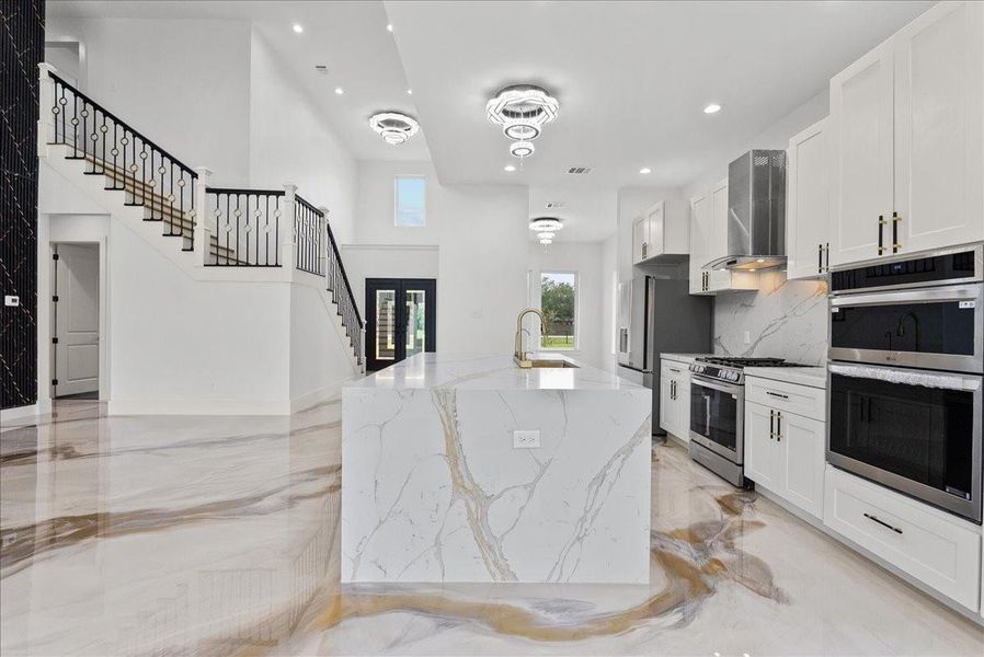 Modern kitchen with sleek finishes, gas range, and double ovens.