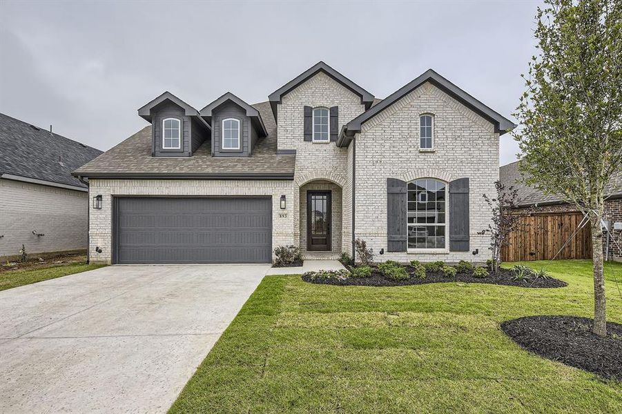 French provincial home with brick siding, concrete driveway, an attached garage, and roof with shingles
